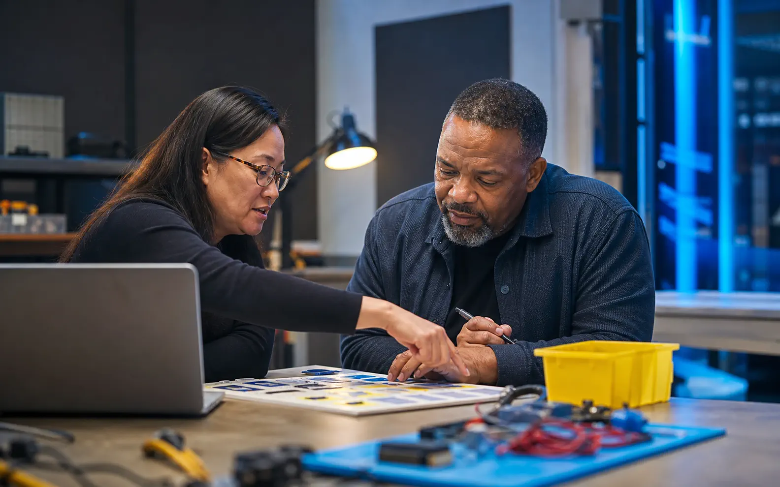 An adult learner and instructor work together on a practical digital project in a workforce lab.